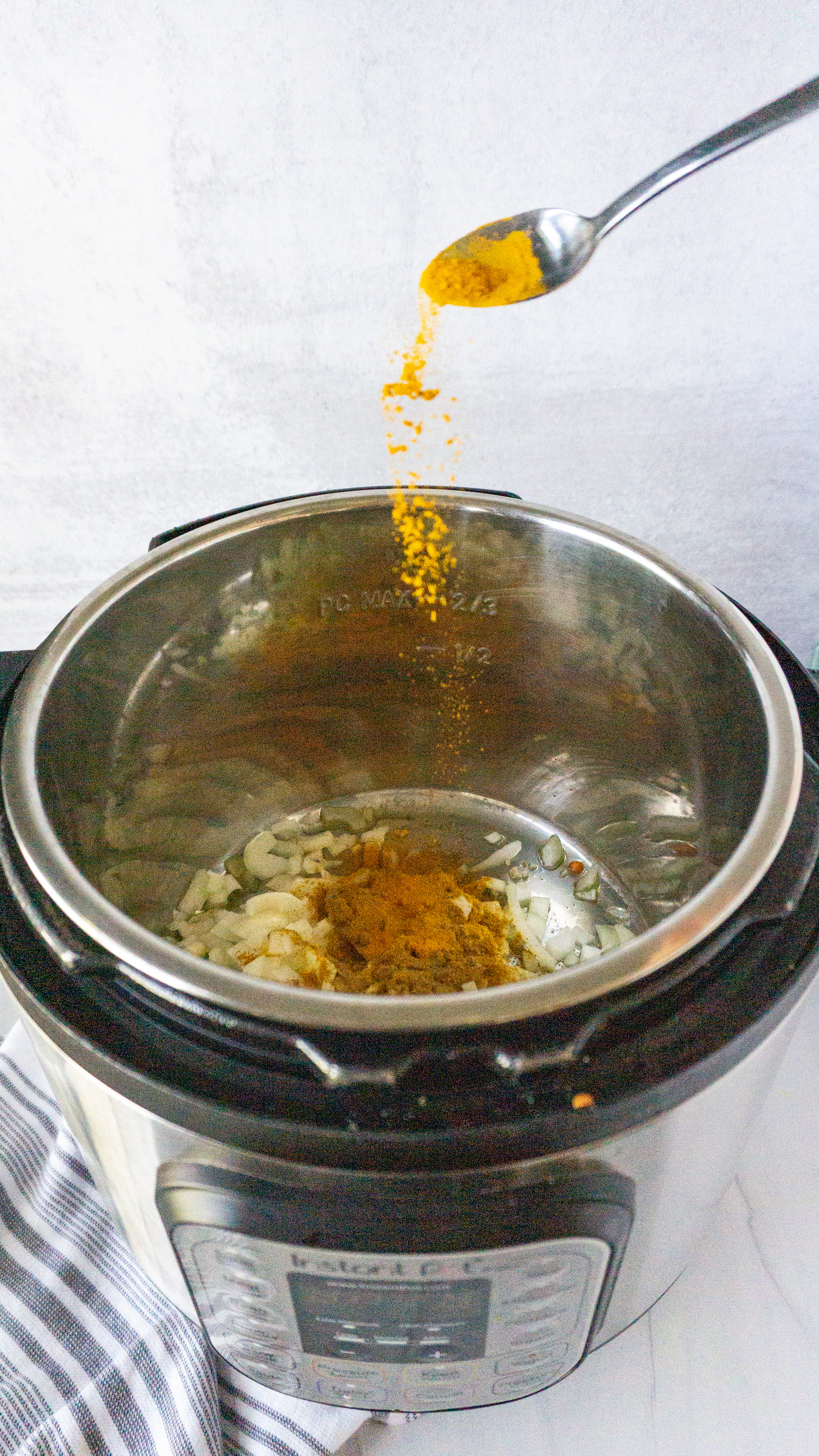 turmeric being poured into instant pot for lentil curry