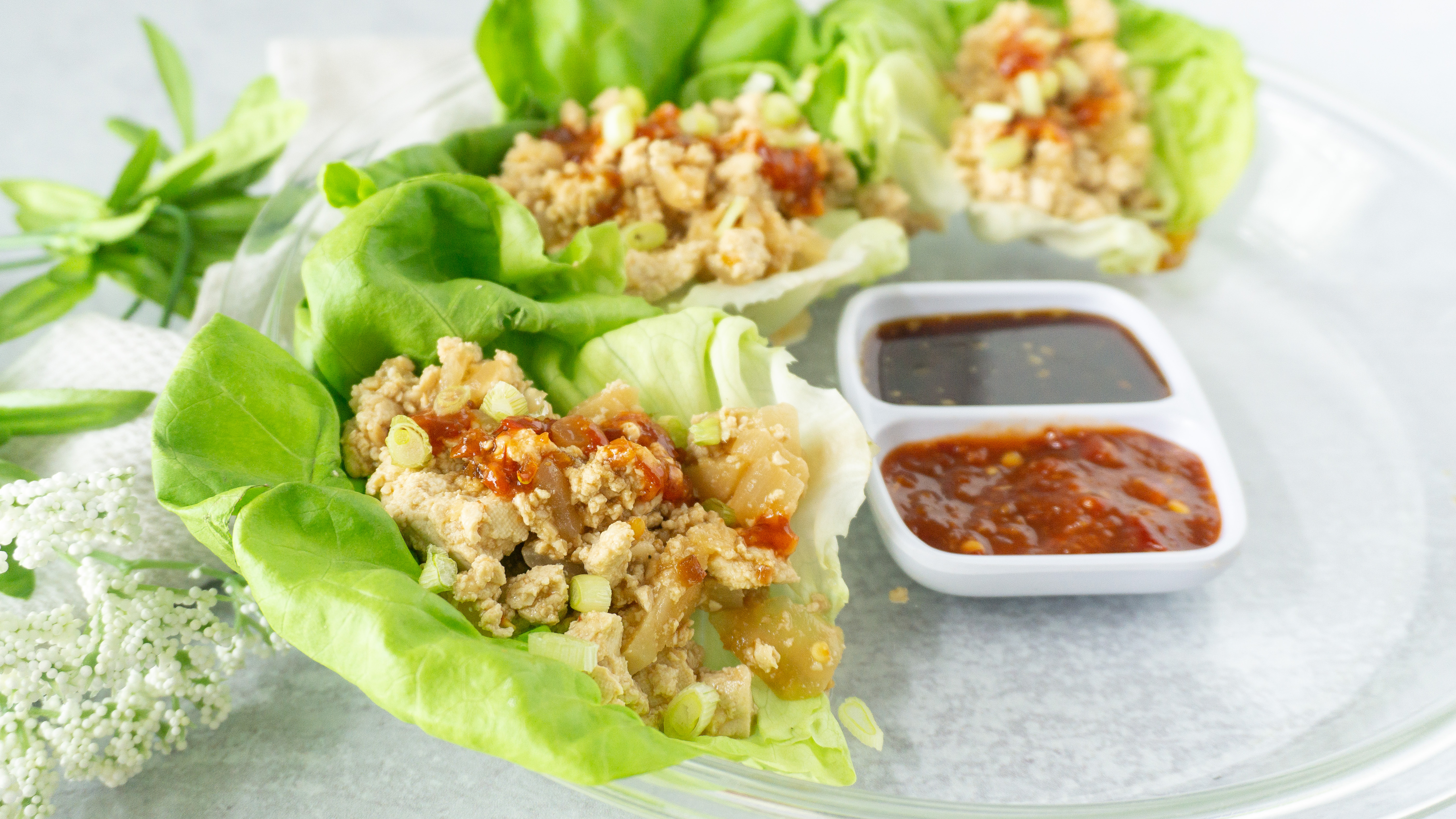 tofu lettuce wraps served on a plate with sauces on the side