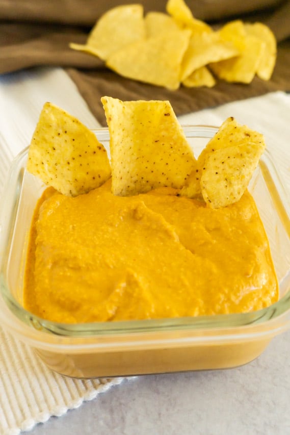 vegan cashew queso with tortilla chips in the bowl and on the side