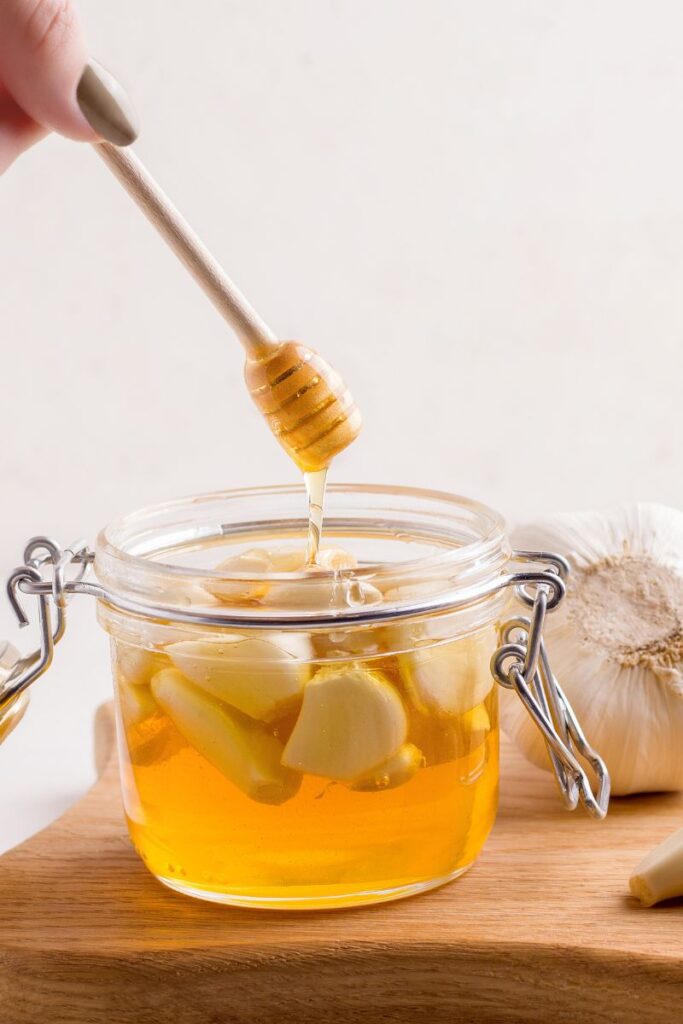 honey being taken out of a honey fermented garlic jar